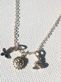 Necklace with three charms on a light gray background
