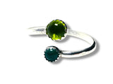 Silver ring with green gemstones on a white background