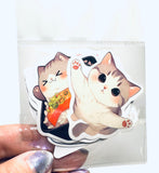 Stack of cat-themed stickers held by a hand with glittery nail polish.