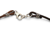 Close-up of a dark brown leather bracelet with silver-toned wire wrapping and a lobster clasp on a white background.