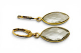 Gold earrings with clear gemstones on a white background