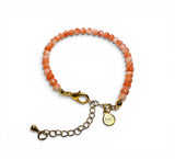 Bracelet with pink beads and gold clasp on a white background