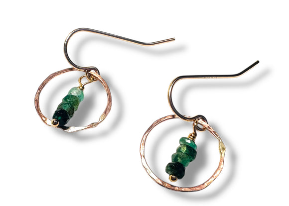 Pair of earrings with green emerald beads on a white background