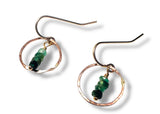 Pair of earrings with green emerald beads on a white background