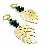 emerald monstera earrings. Gold leaf earrings with green stone accents on a white background