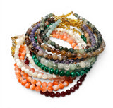 Stack of multicolored beaded necklaces on a white background