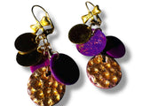 Pair of colorful earrings with gold, purple, and black components on a white background