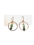 Pair of earrings with circular design and green beads on a white background