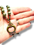 Hand holding a necklace with a decorative pendant on a white background