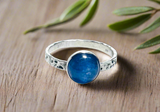 Kyanite Hammered Band Ring, Silver Band Ring with blue stone set in the center. on wood background with fern in the background.