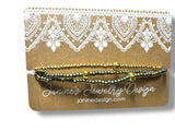 Gold beaded bracelet on a Janine's Jewelry Design card with decorative lace pattern