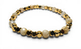 Bracelet with gold, black, and beige beads on a white background
