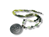 Necklace with green beads and a silver pendant on a white background