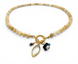 Beaded bracelet with gold charm and gemstone charms on a white background