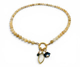 Beaded bracelet with a gold charm and black accent on a white background