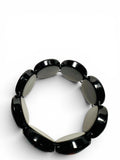 A stretch bracelet made of glossy, oval-shaped links alternating between black and light gray, photographed on a clean white background.