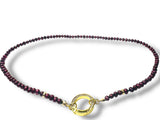Necklace with purple beads and a gold clasp on a white background
