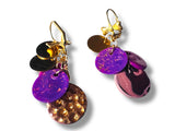 Colorful earrings with purple and gold components on a white background