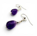 Pair of purple teardrop earrings with silver hooks on a white background