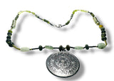 Necklace with green beads and a silver pendant on a white background