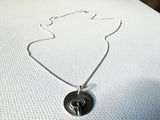 Silver necklace with a pendant on a textured white surface