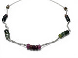 Necklace with multicolored tourmaline beads on wheat chain, a white background