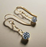 Gold earrings with blue gemstones on a beige background