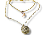 Gold chain necklace with a round pendant and crescent moon charm on a white background