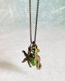 Sea Glass and Sea Creature Necklace green sea glass with brass turtle, starfish and seahorse charm on chain.